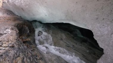 Buzul mağaralarının içinde. Buzun altından akan yeraltı buzulu su akıntısının görüntüsü.
