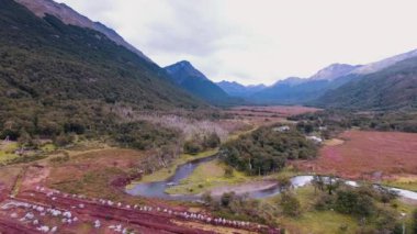 Alp manzarası. Nehrin yeşil orman ve vadi boyunca akan hava manzarası, kayalık dağlarla çevrili. Ushuaia, Tierra del Fuego, Patagonya, Arjantin 'de Sphagnum magellanicum yosunu tarafından oluşturulan kırmızı doğal turba arazisi..