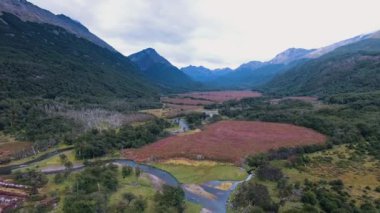 Alp manzarası. Nehrin yeşil orman ve vadi boyunca akan hava manzarası, kayalık dağlarla çevrili. Ushuaia, Tierra del Fuego, Patagonya, Arjantin 'de Sphagnum magellanicum yosunu tarafından oluşturulan kırmızı doğal turba arazisi..