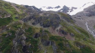 Alp manzarası. Yokuş aşağı akan kayalıkların ve derelerin havadan görünüşü. Ushuaia, Tierra del Fuego, Patagonya 'daki güzel kaya kayalıkları, orman ve karlı dağ zirveleri.