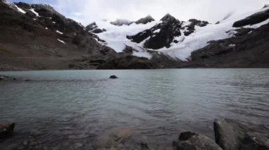 Alp manzarası. Turkuaz renginin büyüleyici görüntüsü dağın tepesindeki saf su gölü. Karlı zirveleri olan kayalık kıyı ve kahverengi dağlar. Arka planda Buzul Vinciguerra.