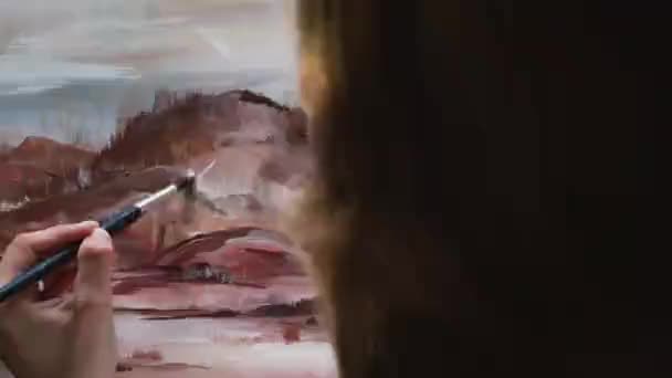 ロマンチックな現代風景を描いた若い女性アーティスト アートとアートワーク アートスタジオで白人女性画家が描いたオーバーヘッドショット 山のピンクのパレットを描いた現代絵画 — ストック動画