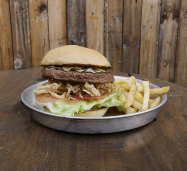 Bitki bazlı burger. Burger değil. NotCo hamburgerin yakın plan görüntüsü. Domates, marul, çıtır soğan halkaları ve NotCo mayonez. Restorandaki ahşap tabakta..