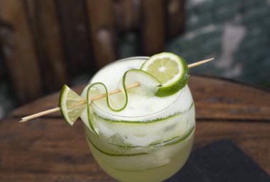 Kokteyller. Limonlu ve salatalıklı cin tonik içerken yakın çekim, ahşap masanın üzerinde.. 