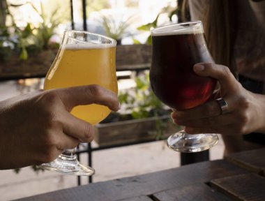 İki kadın kehribar birası ve açık havada sarışın birayla kadeh kaldırıyor..