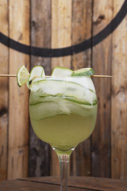 Kokteyller. Limonlu ve salatalıklı cin tonik içerken yakın çekim, ahşap masanın üzerinde.. 