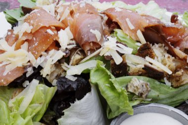 Sezar salatası. Yakından bakınca marul, parmesan peyniri, ekmek, füme somon, pastırma ve Sezar soslu taze Sezar salatası görünüyor..