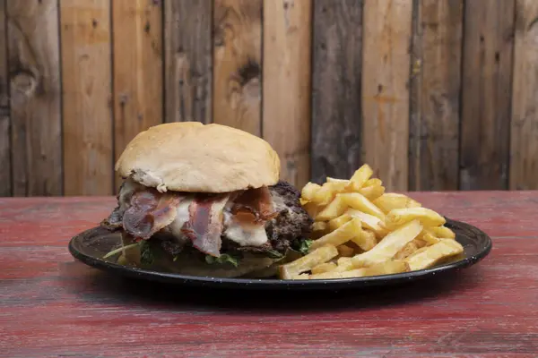 Burger. Closeup view of a hamburger with bacon and fries.