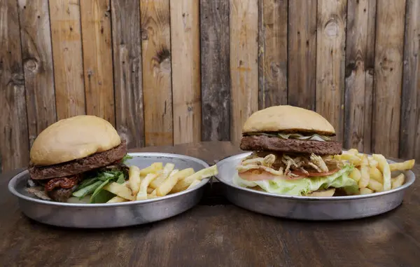 Vegetarian cuisine. Plant based burgers. NotCo Burgers. Closeup view of two NotCo hamburgers in metal dishes on the restaurant wooden table.