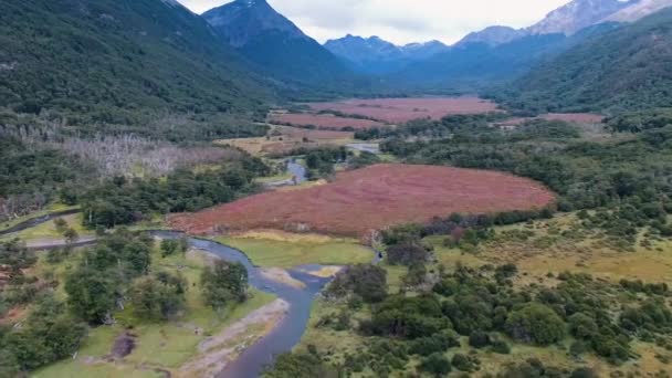 空中俯瞰着流过青翠的森林和山谷的河流 四周环绕着岩石群山 由Sphagnum Magellanicum Moss形成的红色天然泥炭地 — 图库视频影像