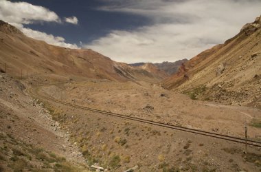 Kırsal demiryolu. Kurak çöl vadisini ve kızıl kayalık dağları aşan tren yolu manzarası. 