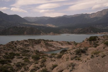 Potrerillos, Mendoza 'daki rezervuarın manzarası. Kurak çevre, turkuaz buzullu su gölü ve arka planda And Dağları. 