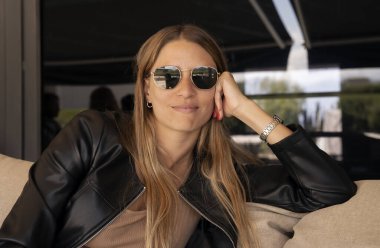 20 'li yaşlarda, güneş gözlüğü takan, siyah deri ceketli, kameraya gülümseyen genç bir kadın.. 