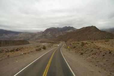 Yolculuk. Kurak çöl ve kayalık dağlar boyunca asfalt karayolu boyunca seyahat ediyor..