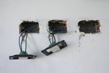 İnşaat halinde. Evin elektrik tesisatı. Işık düğmeleri, fişler ve elektrik kablolarının yakın görünümü son montaj için hazır. 