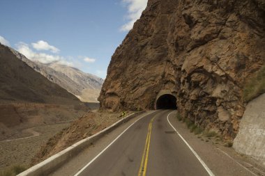 Seyahat et. Aconcagua Dağı yolundaki dağlarda asfalt yol. Yol kayalık tepede bir tüneli geçiyor..