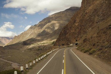 Seyahat et. Aconcagua Dağı yolundaki dağlarda asfalt yol. Yol kayalık tepede bir tüneli geçiyor..