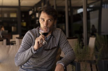 Restoranda bir bardak kırmızı şaraptan içen beyaz bir adamın portresi..