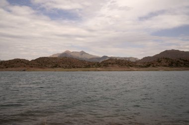 Potrerillos, Mendoza 'daki rezervuarın manzarası. Kurak çevre, turkuaz buzullu su gölü ve arka planda And Dağları.