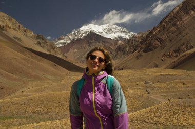 Mendoza, Patagonya, Arjantin 'de yürüyüş ve Aconcagua Dağı. Arka planda Aconcagua Dağı 'ndaki yedi zirveden biriyle poz veren genç bir kadın var.. 