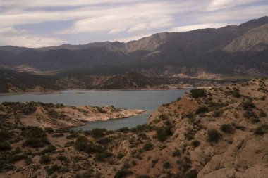 Potrerillos, Mendoza 'daki rezervuarın manzarası. Kurak çevre, turkuaz buzullu su gölü ve arka planda And Dağları.