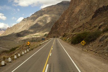 Seyahat et. Dağlarda asfalt yol ve Aconcagua Dağı 'na giden yolda vadi. Yol tepedeki tünelden geçiyor..