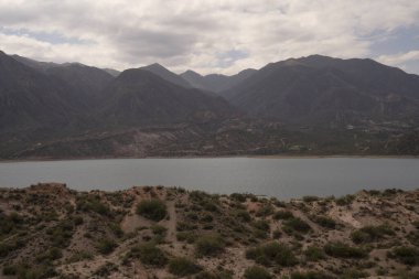 Potrerillos, Mendoza 'daki rezervuarın manzarası. Kurak çevre, turkuaz buzullu su gölü ve arka planda And Dağları. 