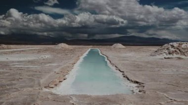 Tuz düzlüklerinde ve dağlarda zaman kaybı. Geçen bulutları ve dramatik gökyüzünü yansıtan bir havuz manzarası. 