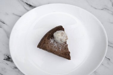 Lezzetli tatlı. Hindistan cevizli mantarlı çikolatalı cheesecake 'in üst görüntüsü, mermer masada beyaz bir tabakta.. 