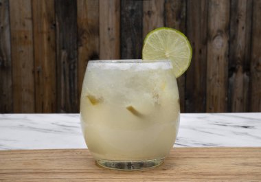 Tropik kokteyller. Bardakta buzlu, limonlu ve şekerli geleneksel bir Caipirinha manzarası.. 