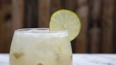 Tropik kokteyller. Bardakta buzlu, limonlu ve şekerli geleneksel bir Caipirinha manzarası.. 