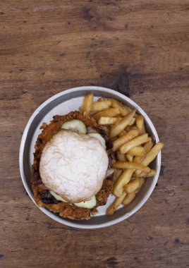 Sandviç. Patates ekmeği, domuz pastırması, salatalık ve patates kızartması ile birlikte ahşap bir tabakta kızarmış tavuklu sandviç..