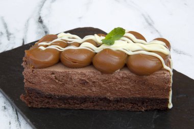 Tatlı tatlılar. Çikolata ve beyaz mermer masa üzerinde, browni tabanlı ve beyaz çikolata figürlü dulce de leche mousse yakın görüntüsü. 