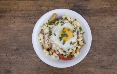 Gurme patates kızartması. Eritilmiş peynir, sucuk, dolmalık biber, soğan ve ahşap bir tabakta ızgara yumurta.. 