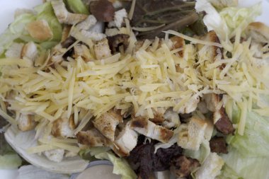 Sezar salatası dokusu. Marul yapraklı Sezar salatası, parmesan peyniri, kızarmış ekmek, domuz pastırması ve Sezar soslu beyaz tabak..