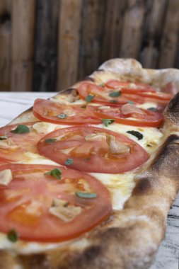 Geleneksel mozarella peynirli Napoli pizzası, kızarmış sarımsak, dilimlenmiş domates ve taze kekik yaprakları.. 