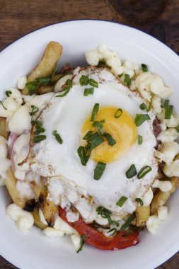 Gurme patates kızartması. Eritilmiş peynir, sucuk, dolmalık biber, soğan ve ahşap bir tabakta ızgara yumurta.. 