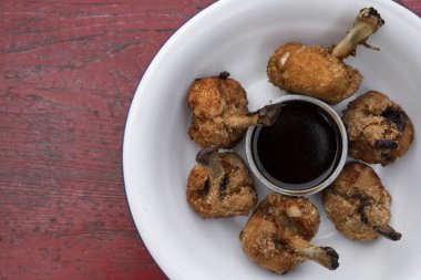Kırmızı ahşap masada beyaz bir kasede acı tatlı soslu kızarmış tavuk kanadı manzarası..