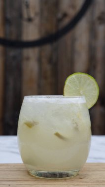 Tropik kokteyller. Bardakta buzlu, limonlu ve şekerli geleneksel bir Caipirinha manzarası.. 