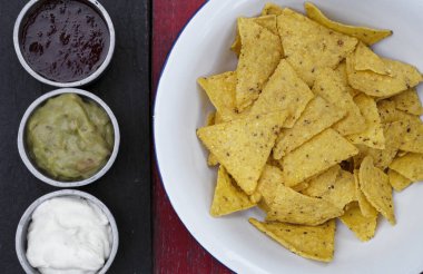 Meksika yemeği. Beyaz kasedeki nachos manzarası ve üç soslu çedar peyniri, acı biber ve guacamole..