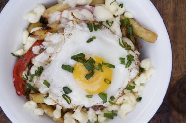 Gurme patates kızartması. Eritilmiş peynir, sucuk, dolmalık biber, soğan ve ahşap bir tabakta ızgara yumurta.. 