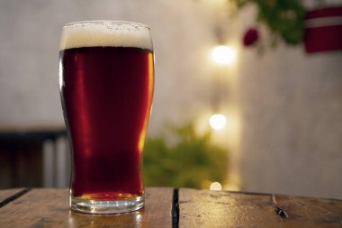 Gece hayatı. Bar masasında taze köpüklü, parlak kırmızı bira.