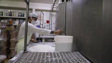 Yiyecek endüstrisi. Endüstriyel dondurma üretimi. Bir fabrika işçisinin beyaz şeker torbasını paslanmaz huni makinesine boşalttığını görmek.