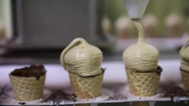 Yiyecek endüstrisi. Dondurma yapımcıları. Konileri çikolatalı dondurmayla dolduran elektrikli bir makinenin yakın görüntüsü.