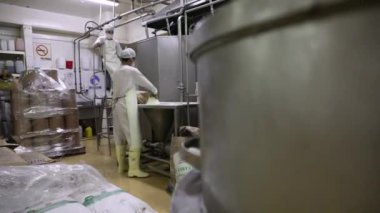 Yiyecek endüstrisi. Endüstriyel dondurma üretimi. Fabrika işçilerinin bir torba vanilya tozunu paslanmaz bir huni makinesine boşalttıklarını görmek.