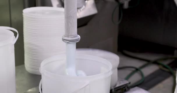 フード産業だ アイスクリーム生産プロセス パイプから商業プラスチック容器に出てくる青い月のアイスクリームのクローズアップビュー 工場労働者がプロセスを導く — ストック動画