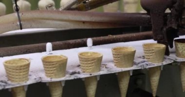 Yiyecek endüstrisi. Otomasyon ve üretim. Çikolatayı külahlara püskürten bir elektrik makinesinin yakın görüntüsü.