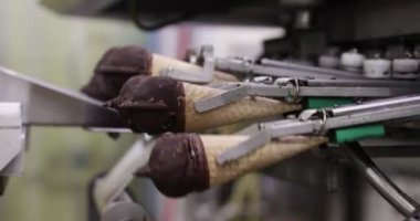 Gıda endüstrisi ve teknoloji. Ticari ambalaj makinesinin çikolata kaplı dondurma külahlarını ve plastik bir pakette fıstığı yakın plan görüntüsü..