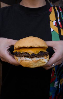 Çedar peyniri ve soğanlı geleneksel bir burger tutan kadın.. 