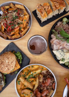 Restoran masasında yemek var. Ahşap arka planda farklı tabak ve tabakların üst görünümü.